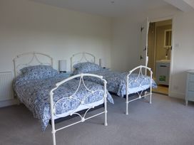 A bedroom with two beds and a doorway leading to a bathroom at Little Evanses, Dalwood, near Axminster