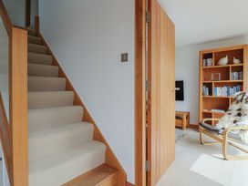 A hallway with stairs and a doorway leading to a sitting area at The Old Log Shed in Honiton