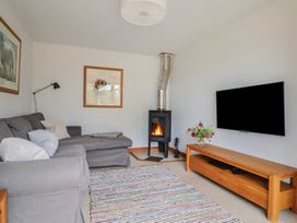 A living room with a sofa and a stove at The Old Log Shed in Honiton