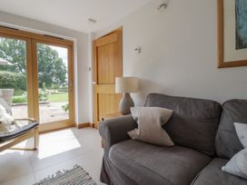 A living room with a sliding door and an armchair at The Old Log Shed in Honiton