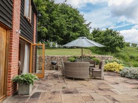A patio with a table and chairs under an umbrella at The Old Log Shed in Honiton