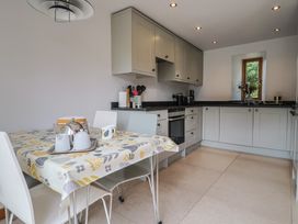 A kitchen with a table and chairs at The Old Log Shed in Honiton