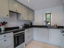 A kitchen with cabinets, countertop, and a window at The Old Log Shed in Honiton