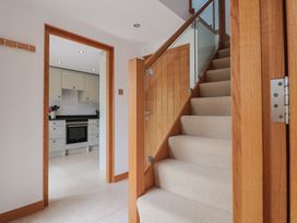 A hallway with a staircase and a view into the kitchen at The Old Log Shed in Honiton