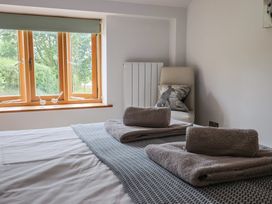 A bedroom with two beds and a window overlooking the garden at The Old Log Shed in Honiton