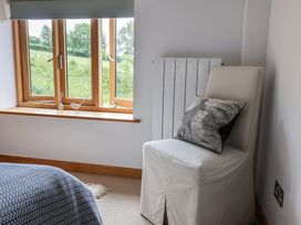 A bedroom with a chair and window at The Old Log Shed in Honiton