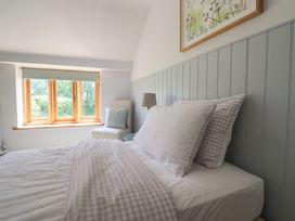 A bedroom with a bed and window at The Old Log Shed in Honiton