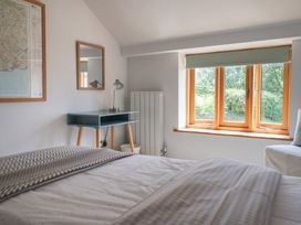 A bedroom with a bed and desk at The Old Log Shed in Honiton