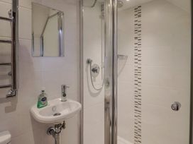 A bathroom with a shower, hand basin, and towel rail at The Old Log Shed in Honiton