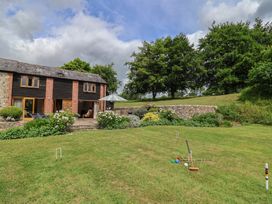 An outdoor view of a garden with a house and croquet set at The Old Log Shed in Honiton