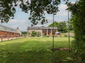An outdoor space with a house and swing at The Old Log Shed in Honiton