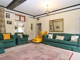 A living room with green sofas and an armchair at Hornshayne Farmhouse, Farway, near Honiton