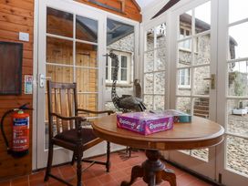 A conservatory with a table, chair, board games and a statue at Hornshayne Farmhouse Farway, near Honiton