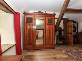 A bedroom with wardrobe and chair at Hornshayne Farmhouse, Farway, near Honiton