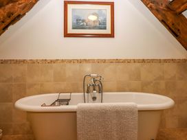 A bathroom with a bathtub and wall art at Hornshayne Farmhouse Farway, near Honiton