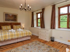 A bedroom with a bed and windows at Hornshayne Farmhouse, Farway, near Honiton