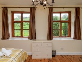 A bedroom with a bed and windows at Hornshayne Farmhouse, Farway, near Honiton