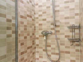 A shower with tiled walls and shower fixtures at Hornshayne Farmhouse in Farway, near Honiton