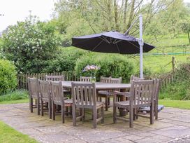 An outdoor dining area with a table and chairs at Hornshayne Farmhouse Farway, near Honiton