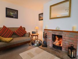 A living room with a fireplace and sofa at Poppy Cottage in Charlton Marshall