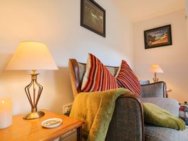 A living room with a sofa and lamps at Poppy Cottage in Charlton Marshall