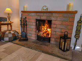 A living room with a fireplace and a pouffe at Poppy Cottage in Charlton Marshall