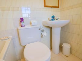 A bathroom with toilet, sink and cleaning supplies at Poppy Cottage Charlton Marshall