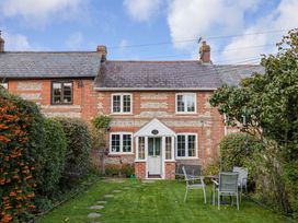 A garden with a house and patio furniture at Poppy Cottage in Charlton Marshall