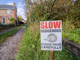 A sign urging to drive carefully for hedgehogs near a path and house in Charlton Marshall