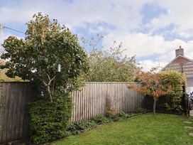 A garden with trees and a fence at Poppy Cottage in Charlton Marshall