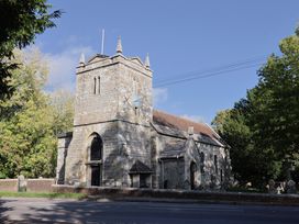 A church building with a tower and clock at Poppy Cottage in Charlton Marshall