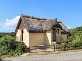 A cottage with a thatched roof and steps leading to the front door at The Cottage in Sampford Courtenay