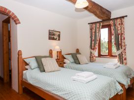 A bedroom with two beds and a window at The Cottage in Sampford Courtenay