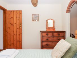 A bedroom with a bed, dresser, and mirror at The Cottage in Sampford Courtenay