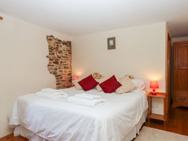 A bedroom with a bed and red pillows at The Cottage in Sampford Courtenay