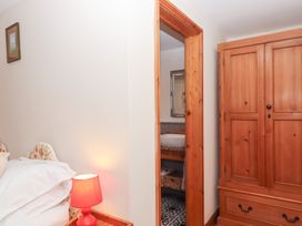 A bedroom with a wardrobe and a bathroom entrance at The Cottage in Sampford Courtenay