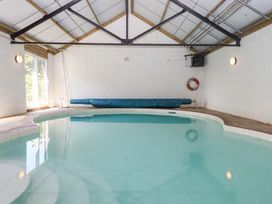 An indoor pool area with a swimming pool and pool cover at The Cottage in Sampford Courtenay