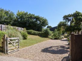 A gravel driveway with a gate and trees at The Cottage in Sampford Courtenay