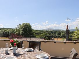 An outdoor dining area with a table and chairs overlooking a landscape at The Cottage in Sampford Courtenay