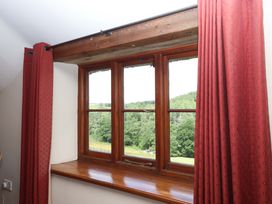 A window with curtains overlooking fields at Hope Cottage in Riddlecombe, near Winkleigh