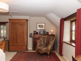 A bedroom with a wardrobe, chair, and table at Hope Cottage, Riddlecombe, near Winkleigh