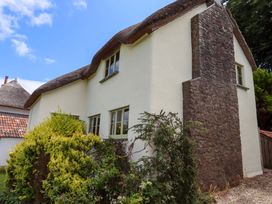 A house with a thatched roof and stone wall at Hope Cottage, Riddlecombe, near Winkleigh