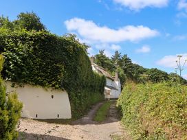 A dirt path leading to a thatched roof house at Hope Cottage in Riddlecombe, near Winkleigh