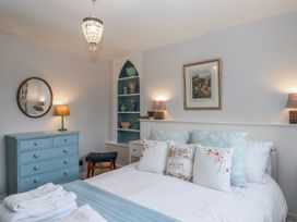 A bedroom with a bed, nightstands, and decorative items at Chapel Cottage in Welcombe