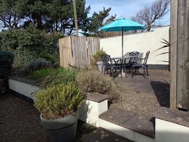 A garden with a table and chairs under an umbrella at Saltwind Granary Clovelly