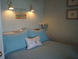 A bedroom with a bed and wall art at Coach House Cottage in Strete, near Dartmouth
