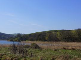 A lake surrounded by grass and trees near hills at Coach House Cottage Strete, near Dartmouth