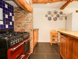 A kitchen with stove, cabinets, and plates on the wall at East Bickleigh in Halwell