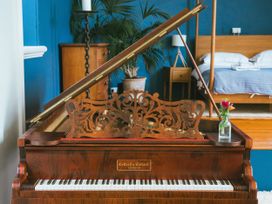 A piano with a flower vase in a bedroom at The Music Room in Aveton Gifford