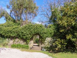 A garden with an archway and pathway at The Music Room near Aveton Gifford